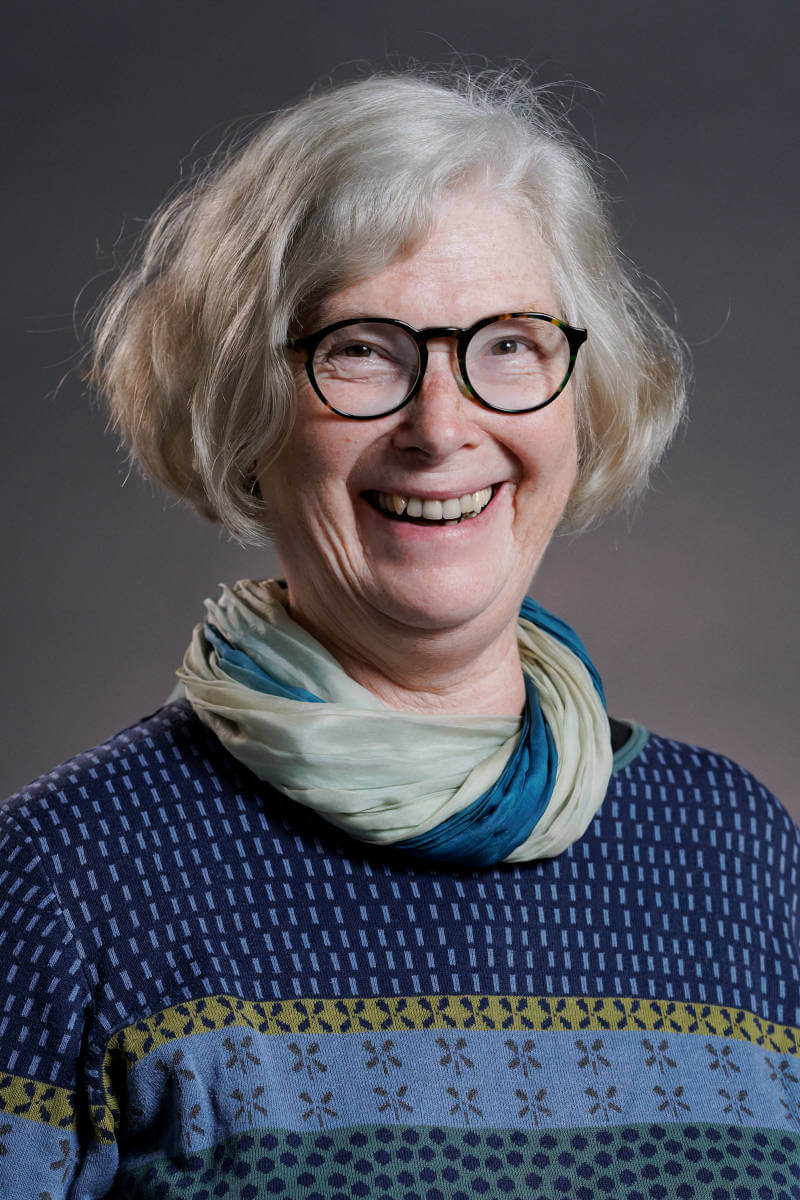 Porträtfoto von der Ergotherapeutin Ingrid van Essen vor grauem Hintergrund